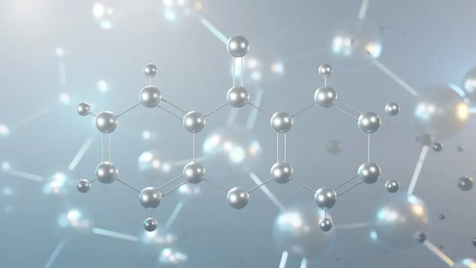 Silvery 3D molecular model with two linked ring structures against a blurred background of floating spheres